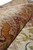 Rolled silk pile showing the sheen shift across mauve border and ivory hunting field
