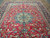 Blue and ivory central medallion framed by scrolling arabesque vines across the soft red Esfahan field