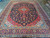 Full view of the large Persian rug showing symmetrical borders, corner spandrels and navy ground