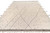 Large area rug photographed at an angle showing charcoal dots scattered across the ivory beige field