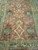 Wool pile detail showing serrated leaf palmettes, cream diamond medallion and olive green main border