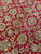 Detailed wool pile close-up of burgundy field with sage palmettes, cream blossoms and curling acanthus leaves