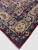Corner detail of blue floral border, ivory guard band and red selvage on antique wool rug