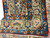 Folded corner revealing dense hand-knotted wool pile, ivory floral border and soft cotton fringe