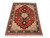 Angled floor view of rust red Tabriz rug with navy floral border and ivory corner spandrels