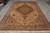 Large 8x12 Oriental rug displayed lengthwise on grey tile floor with ivory fringe ends