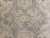 Macro shot of ivory and gold palmette drawing over grey wool pile knot rows