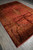 Diagonal full-length shot of 9x12 antiqued Kashan rug with pink fringe and rust field