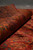 Rolled edge of the wool rug showing pile depth, sheen and antiqued rust coloring
