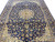 Persian Isfahan rug laid flat on floor, dense all-over floral field in navy and gold tones
