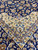 Ivory corner spandrel with curling vinework meeting the navy floral field and layered guard stripes