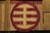 Close-up of burgundy circular roundel motif woven in ivory and olive on gold ground