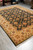 Traditional all over floral rug laid in warehouse with rolled rugs stacked along the back wall