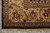 Corner detail of ivory and olive borders with gold rosettes above the cotton fringe