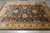Black and gold hand-knotted Oriental rug displayed on grey plank flooring showing all-over palmette field