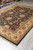Angled floor shot showing black field, olive guard border and hand-knotted pile of this room size rug