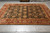 Hand-knotted Indian rug displayed flat on grey tile showing gold palmettes across a deep black field
