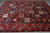 Angled view of the panel field and wide red border with ivory vinework and navy rosettes