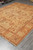 Angled floor view of the hand-knotted wool rug showing honey gold field and terracotta palmettes