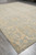 Angled view of 9 by 12 wool area rug corner with ivory fringe and beige border