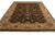Angled floor view of black wool area rug with scrolling vines and cream floral border