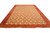 Angled full length view of large coral wool rug showing golden rosette lattice and plain border