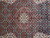 Close-up of ivory lobed medallion with tiny fish leaves in red, turquoise and navy wool