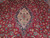 Ivory and green medallion detail ringed by rose blossoms on deep cherry red wool