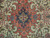 Close-up of coral and navy geometric medallion with turquoise rosettes on ivory Persian field