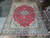 9'8" x 13'5" Persian Isfahan rug displayed flat on showroom floor beside rolled rugs