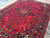 Angled view of the hand-knotted wool pile showing gold vinework, teal leaves and crimson ground