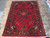 8'3 x 11'4 hand-knotted Persian rug on travertine tile, red field framed by navy border