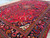 Wide corner angle across the crimson field and black border filled with palmettes and blossoms