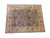 Angled full view showing hand-knotted wool rug, denim blue all-over floral field, celadon green wide border
