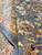 Close-up of folded pile edge revealing dense hand-knotted wool, apricot and burgundy floral detail