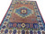 Angled view of red and blue Mamluk design rug with cypress motif navy end panel