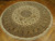 8x8 round Oriental rug angled on wood floor, ivory field with sage green inner border