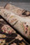 8x10 Afghan Zigler rug rolled to show thick natural wool pile and ivory border