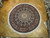 8'8" x 9'4" round Oriental rug displayed on parquet showroom floor with ivory fringe