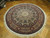Angled view of 9x9 round hand-knotted rug showing dome layout and wide floral border