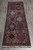 Hand-knotted wool runner photographed on grey tile showing stepped diamond medallions and ivory fringe ends
