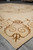 8'6" x 11'6" Tibetan wool and silk rug angled on showroom floor showing scrolled medallion