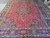 Angled full view of the 9'8 x 13'5 Mashad rug showing 4 border bands and red field