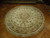 Angled floor view of the cream round area rug showing hand-tied ivory fringe around the entire edge