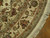 Border detail showing curved sage guard bands, burgundy roses and hand-tied ivory fringe on wood floor
