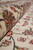 Folded edge detail revealing plush pile depth, rose motifs and hand-knotted construction from the side