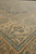 Angled view across the golden border showing hand-spun wool texture and muted blue green flowerheads