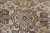 Close-up of dark brown medallion outlines against a sandy beige field with cool gray shading