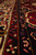 Low angle across the navy guard border showing dense hand-knotted wool pile and floral rosettes