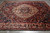 9x12 Bakhtiar Persian rug angled on grey floor, burgundy field with ivory border and blue spandrels